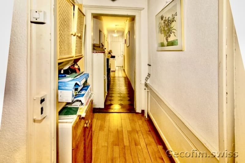 Hardwood floor, radiator, white walls, wooden cabinets, picture frame, hallway lighting