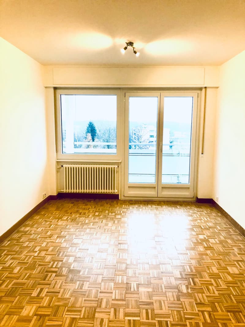 empty room, wooden parquet floor, large windows, sliding glass doors, balcony, white radiator