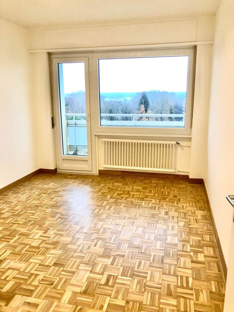empty room, wooden parquet floor, white walls, large window, balcony, radiator