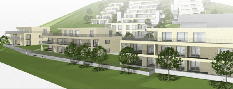 Aerial view of a residential building complex with multiple buildings, balconies, and a green hill in the background