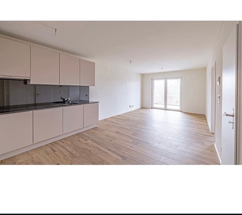 Empty kitchen with modern cabinetry, tiled floor, double glass doors to balcony, sink, black countertops