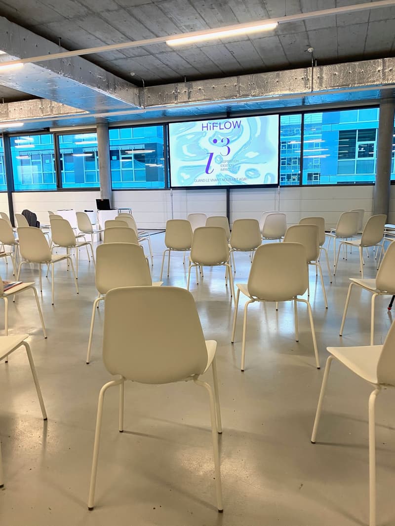 large open room, many white chairs, projector screen, large windows
