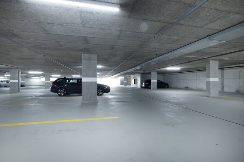 Parking lot with a row of pillars and cars parked on both sides, yellow line markings