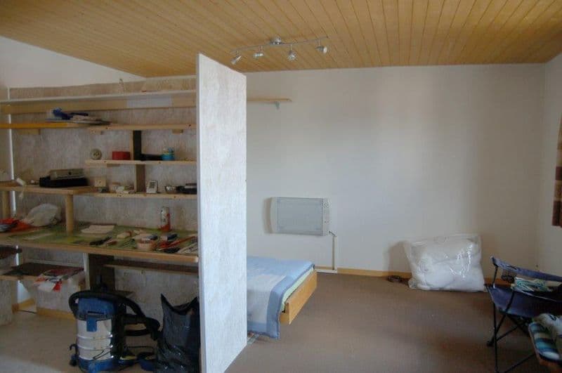 small room with a bed, desk, shelves, and a chair