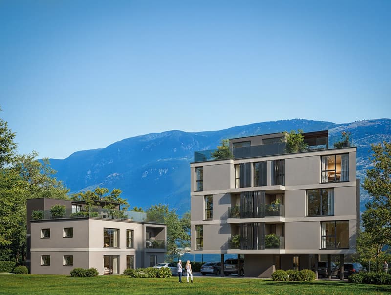 Modern apartment buildings with balconies, surrounded by greenery and mountains
