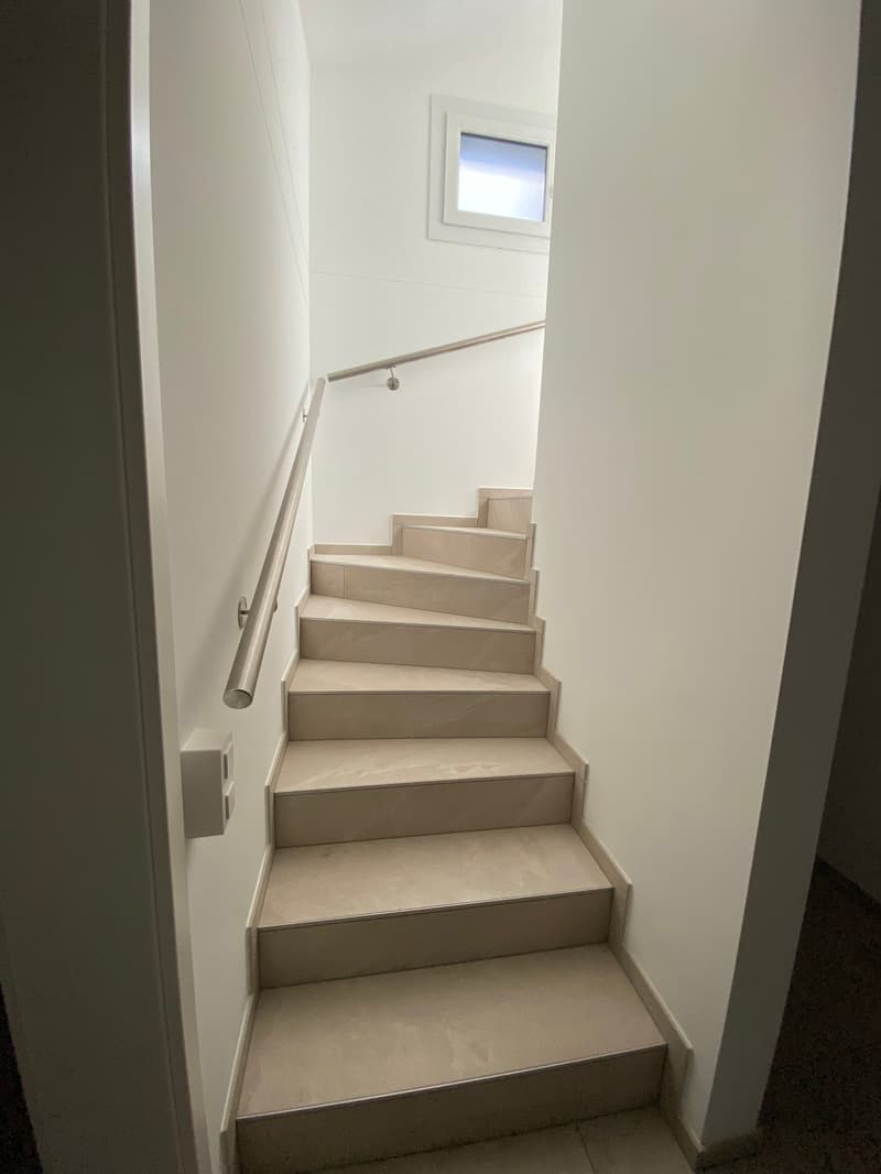 Modern staircase with light gray steps and white walls