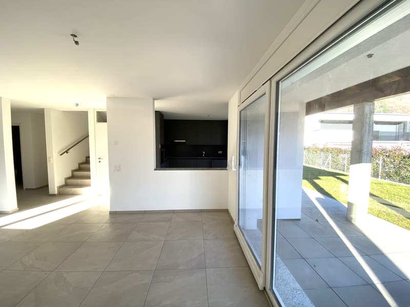 Empty living space, tiled flooring, sliding glass doors, light reflecting on floor, open view to stairs and outdoor area