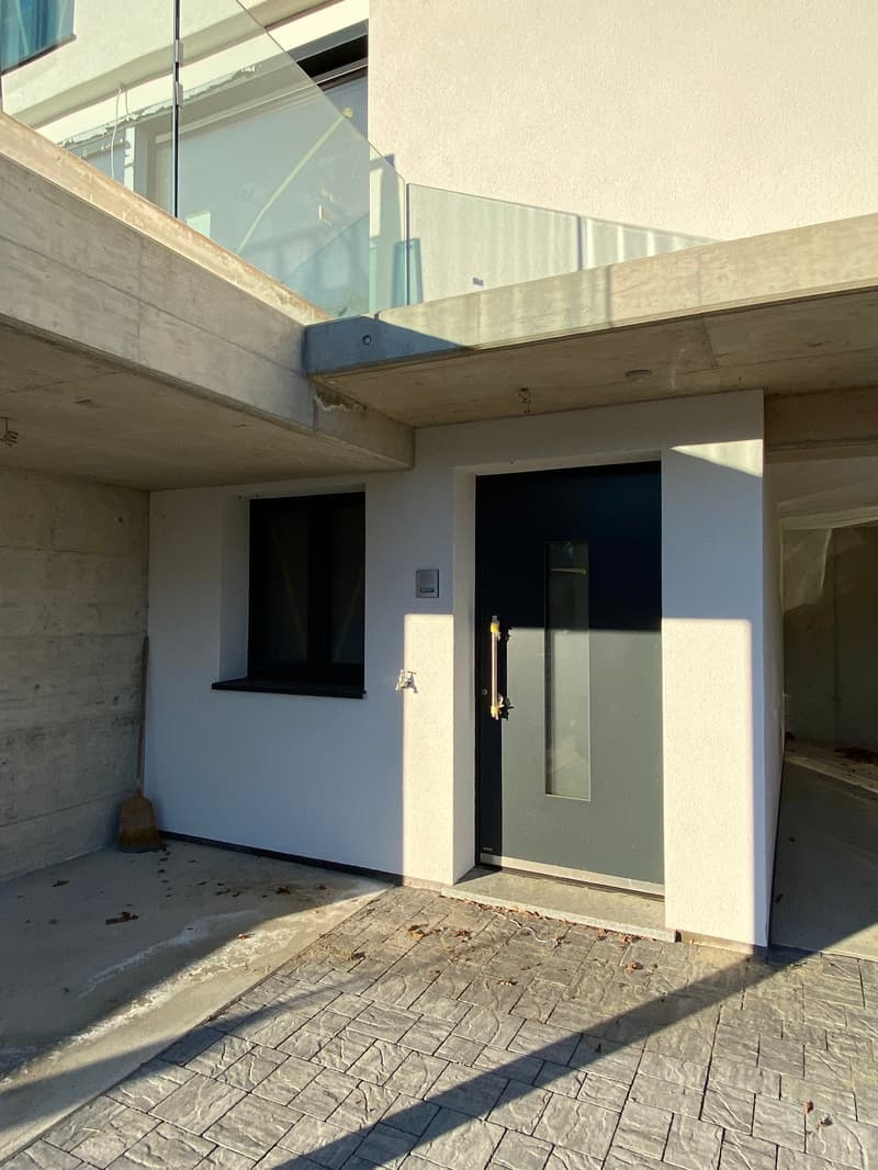 raised ground floor, concrete wall, gray door, glass window, tiled floor