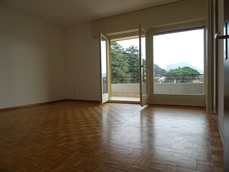 Wooden floor, Open sliding doors to balcony, white walls, view of trees and mountains