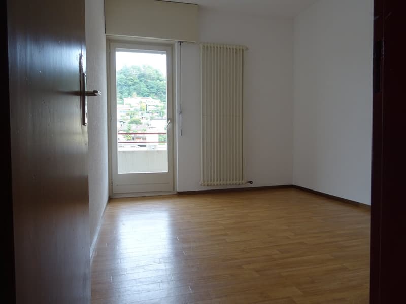 empty room with balcony and window, wooden floor, white walls, white radiator