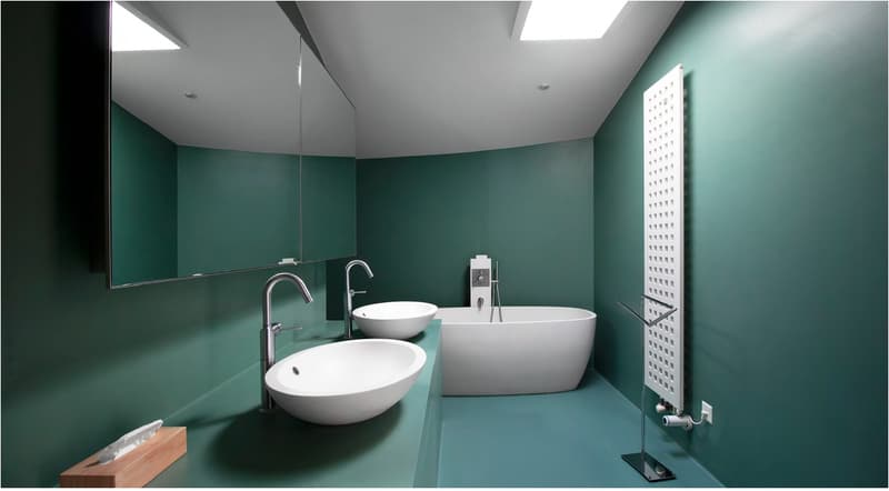 Bathroom with green walls, two sinks, a bathtub, and a mirror. The room has a modern and minimalist design.