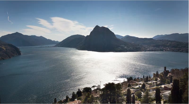 Aerial view of a serene lake with mountains and a small town in the background.