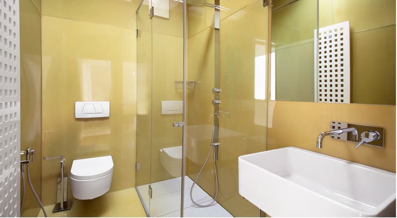 Modern bathroom with glass shower enclosure, white toilet, and white sink.
