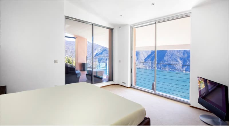 Spacious bedroom with a bed, sliding glass doors leading to a balcony, and a flat screen TV.