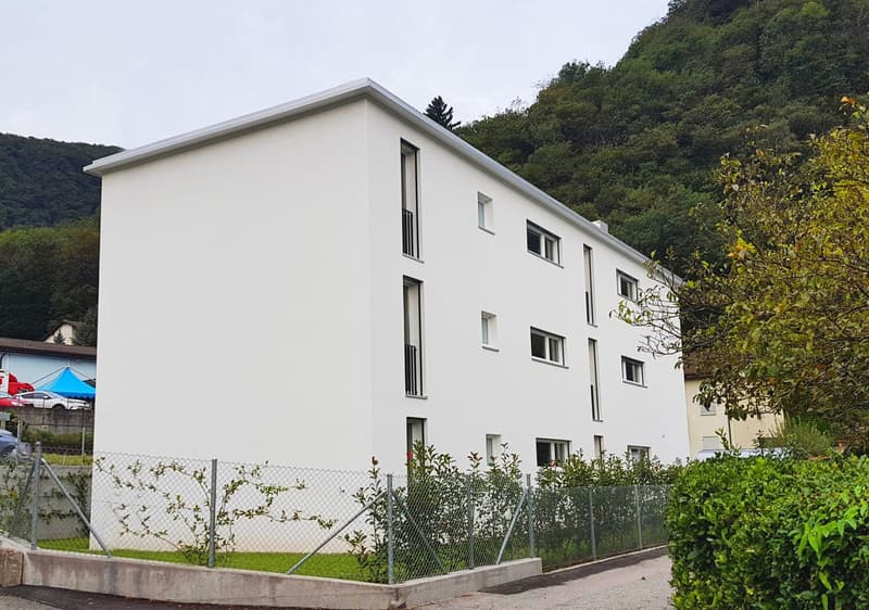 white building, several windows, fenced area, mountain in the background