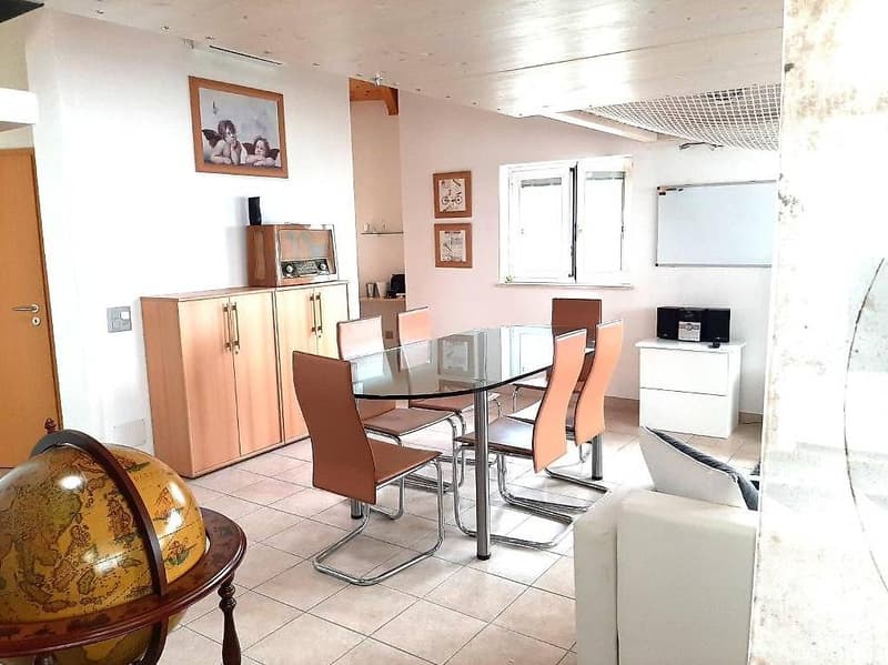 Dining room, round glass table, wooden cabinets, sofa, floor lamp, desk, frames on the wall, blackboard, globe
