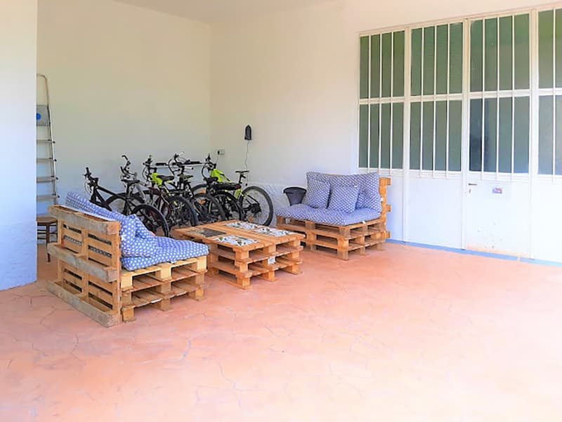 outdoor seating area, wooden pallets, tables, bicycles, white walls, windows, ladder