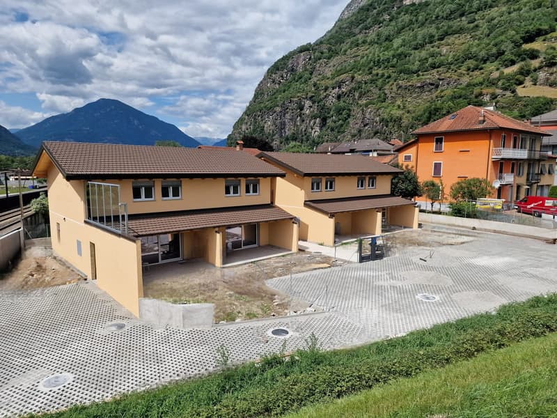 Newly built house, yellow exterior, brown roof, large windows, driveway, mountains in the background