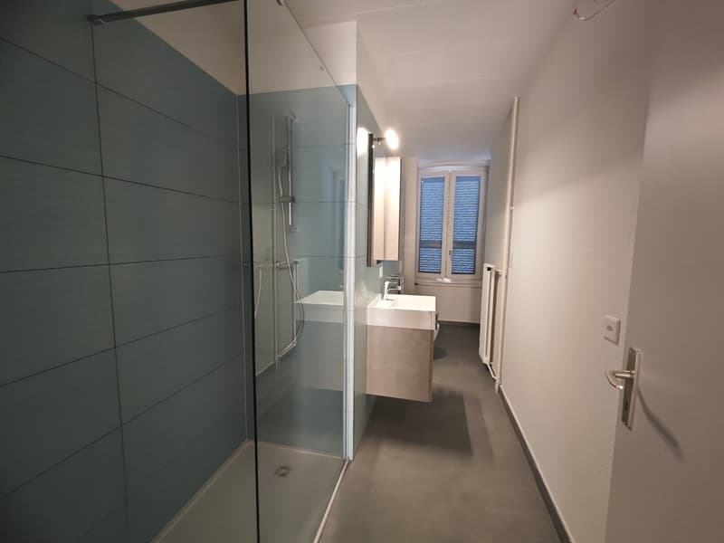empty bathroom with glass shower, white sink, and blue tiled walls