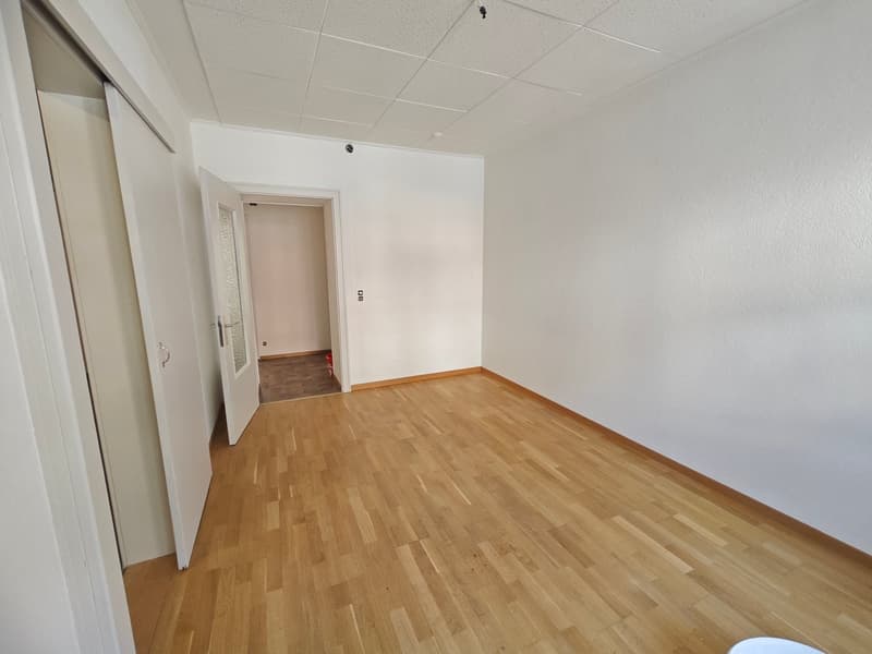Empty room with wooden floor, white walls, and two doors.
