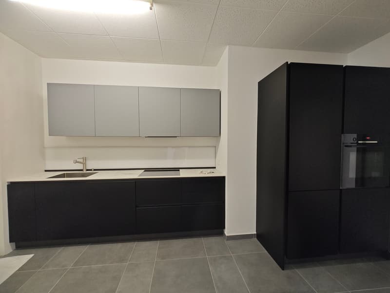 modern kitchen with black cabinets, white countertops, stainless steel sink, gas stove, refrigerator, tiled floor