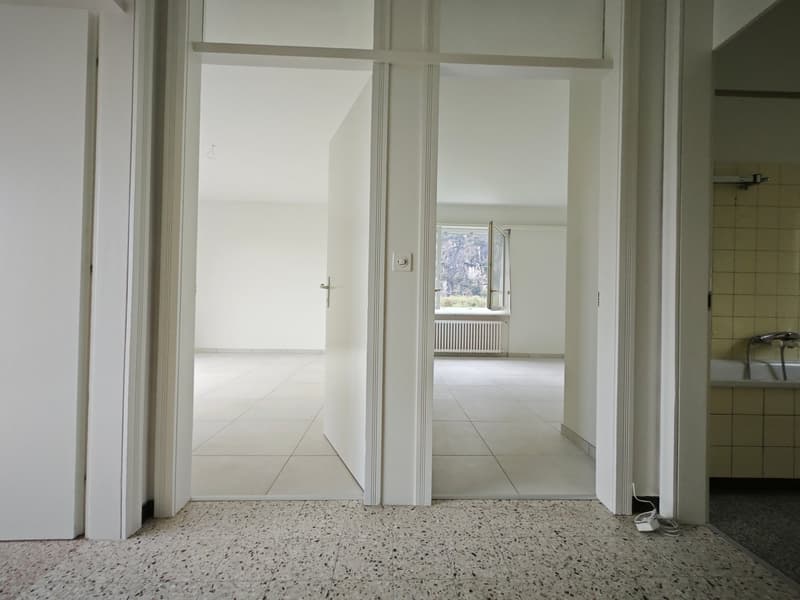 Open layout, white walls, white tiled floors, entrance doors, window, radiator