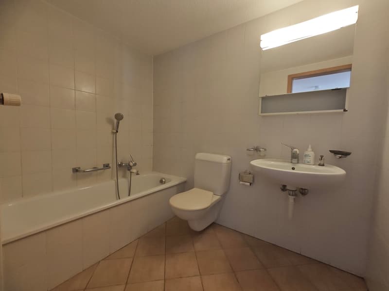 Bathtub, toilet, sink, mirror with shelf, towel rack, white tiles, wooden floor