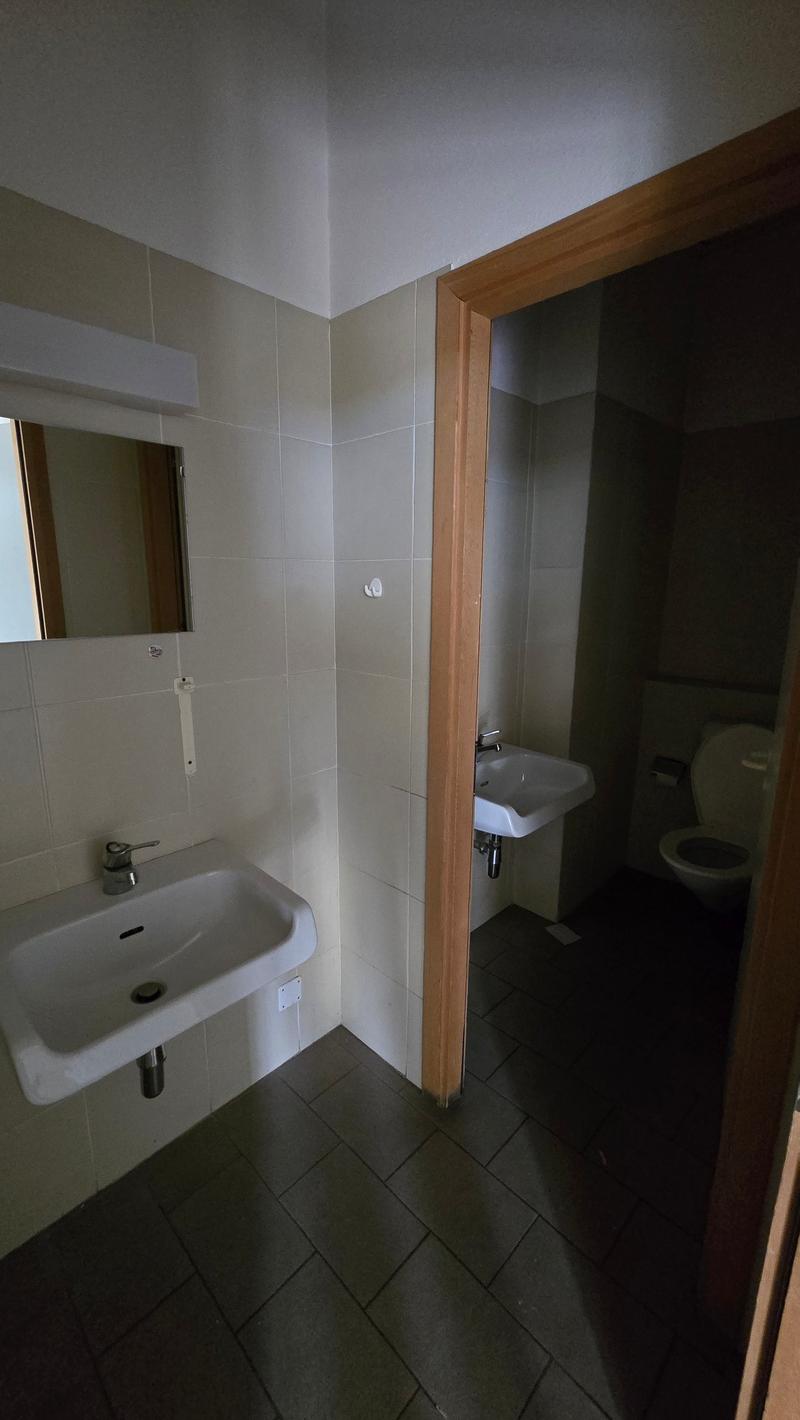 Bathroom with a sink, mirror, and toilet. The sink has a faucet and soap dispenser. The toilet is visible in the adjacent area.