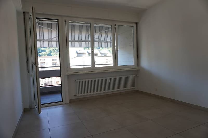 Empty room with balcony, radiator, white walls and floor, large windows