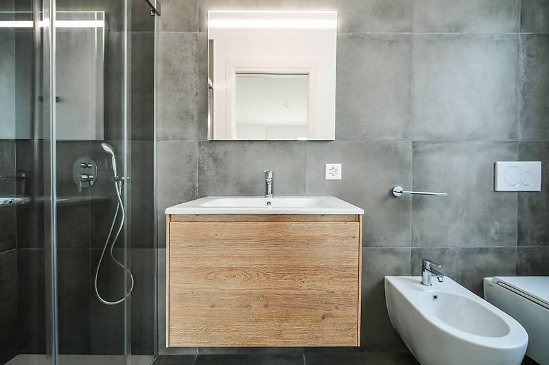 modern bathroom with gray tiles, wooden vanity, white sink, modern shower, white bidet and toilet