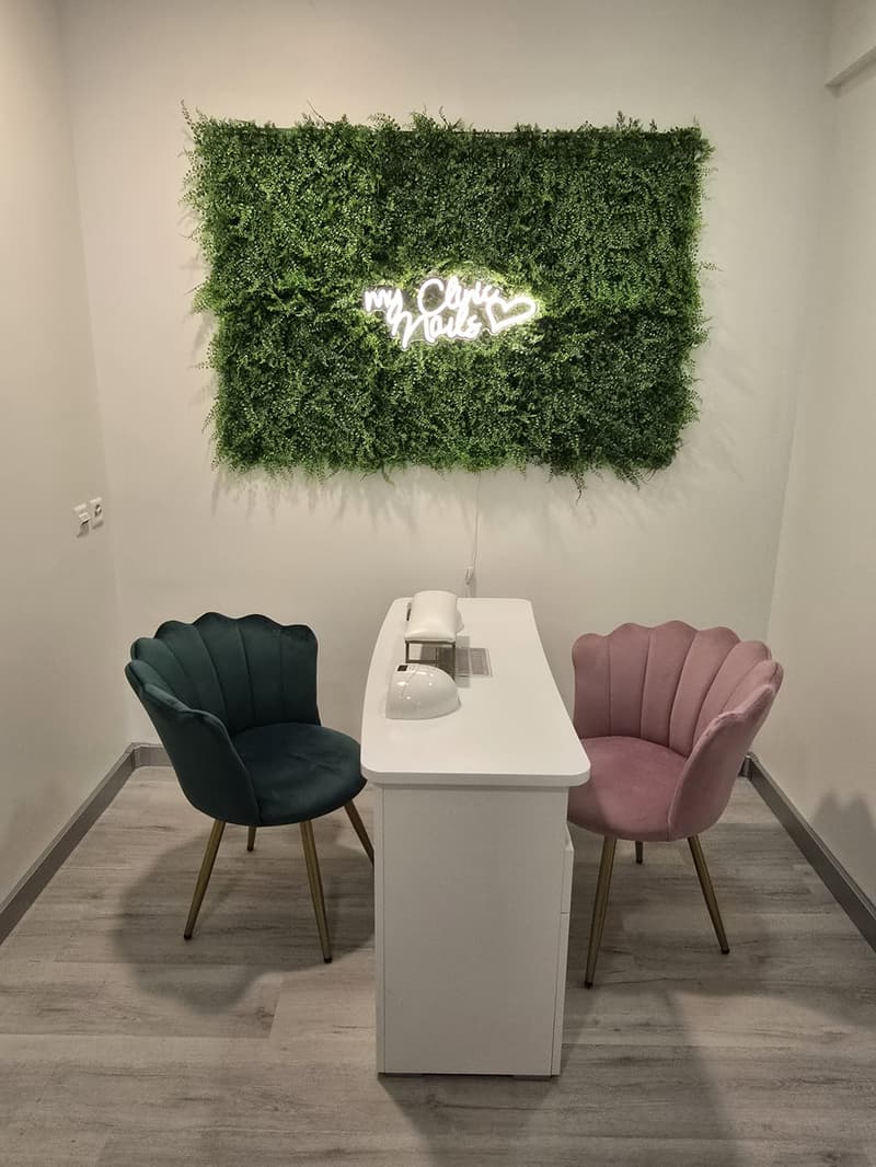 white desk, two chairs, green wall decoration with white text, hardwood floor