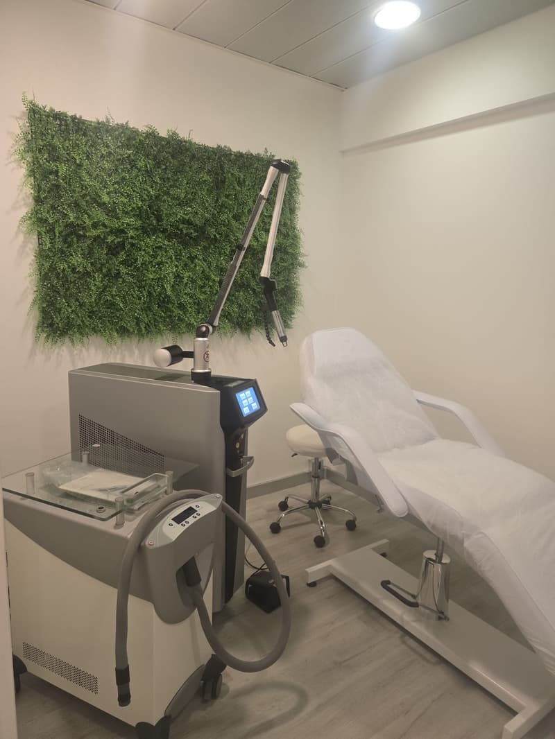 Room with a treatment chair, medical equipment with screen and hose, green wall, light overhead, wooden floor
