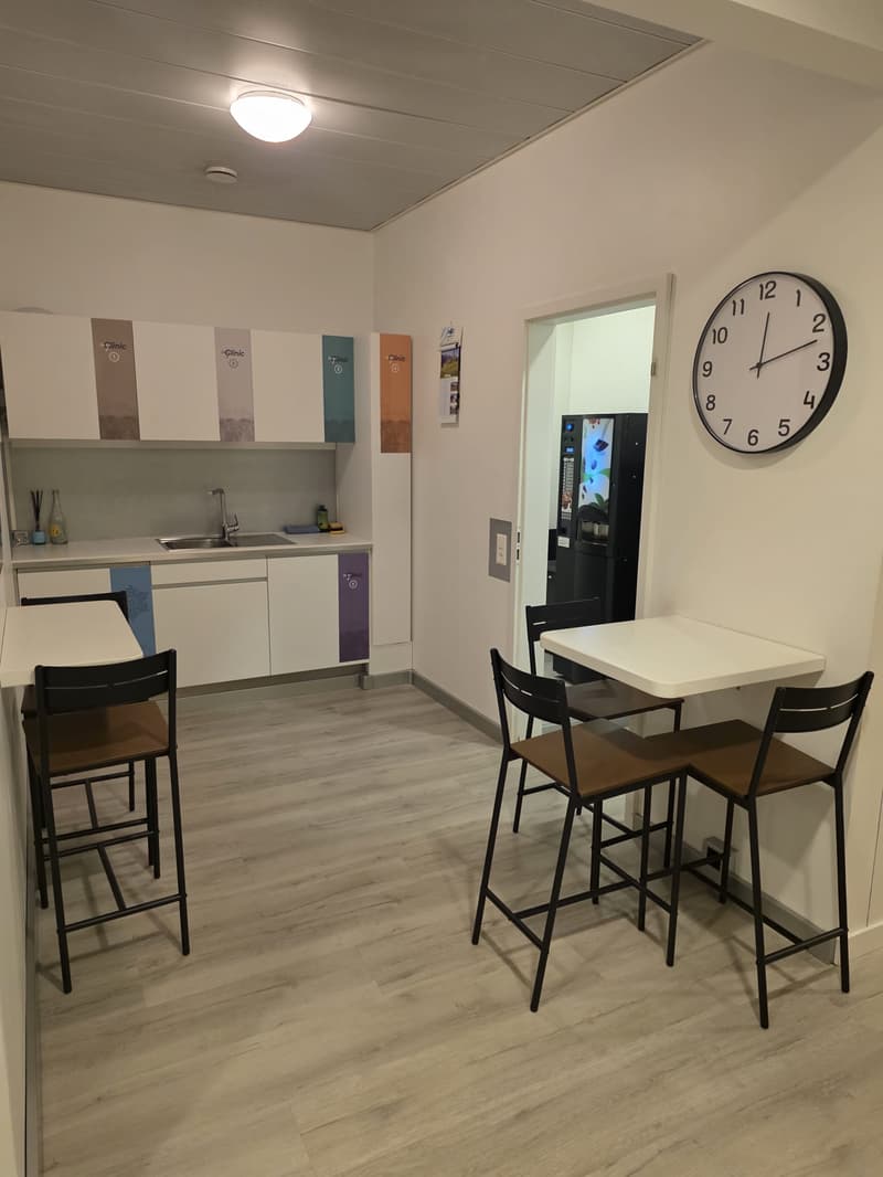 Counter and chairs, sink, clock, and vending machine in the room