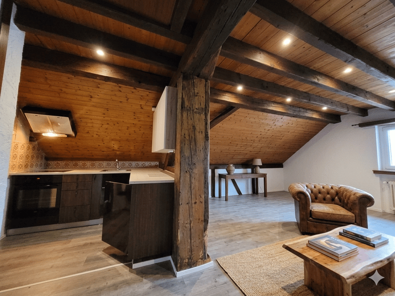 Open kitchen, living room, wooden beams, wooden floor, radiator, coffee table, armchair, table, lamp