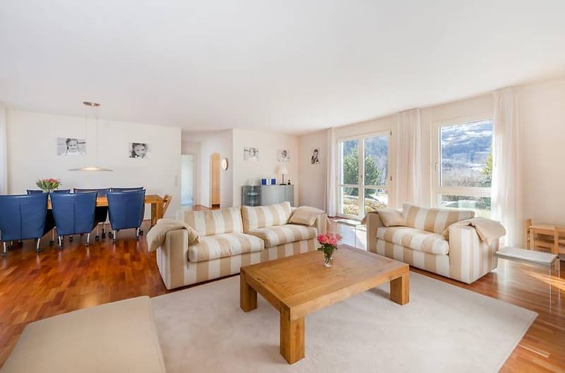 Two striped sofas, wooden coffee table, dining table with chairs, large windows