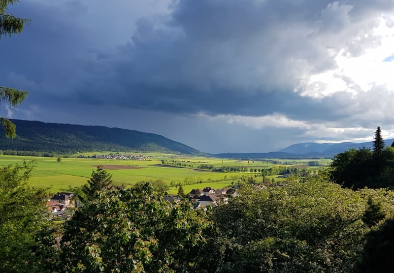 green field, mountains, small village, cloudy sky