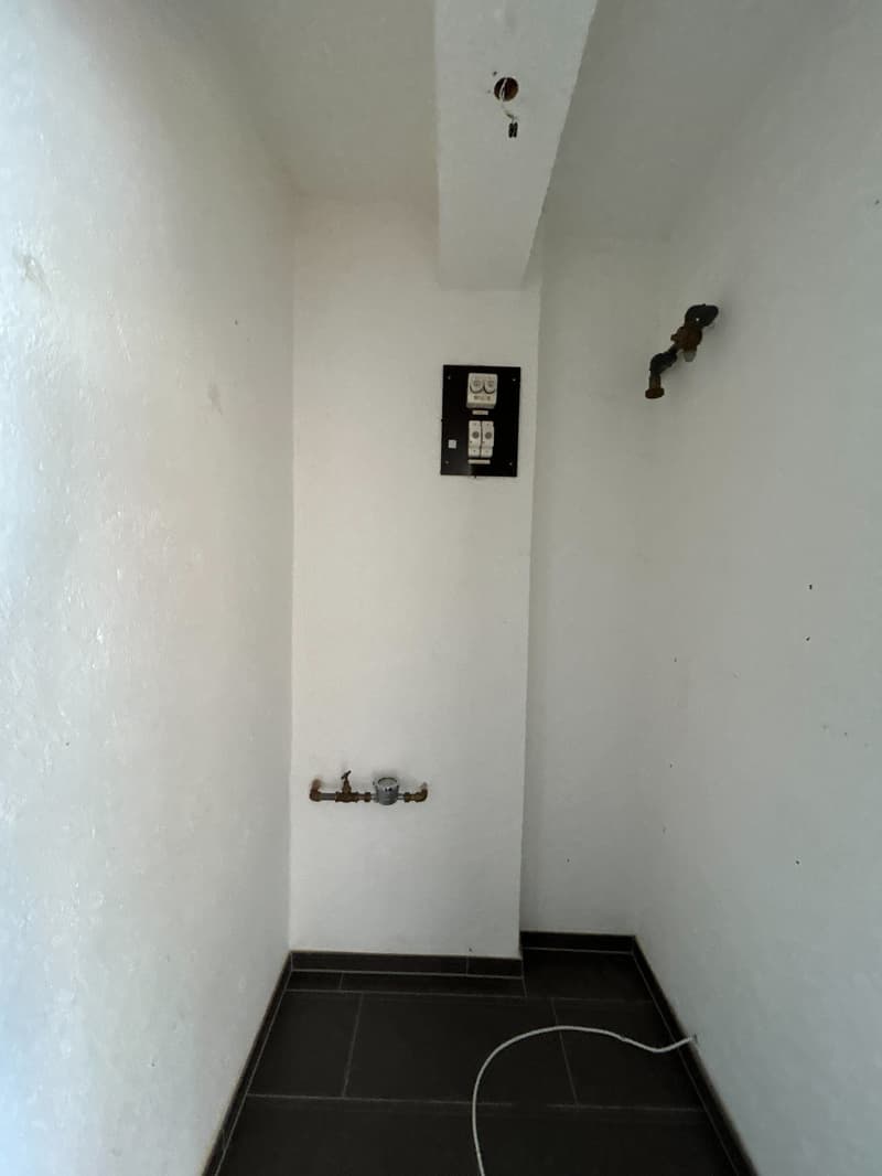 empty room, white walls, black tiled floor, electrical panel