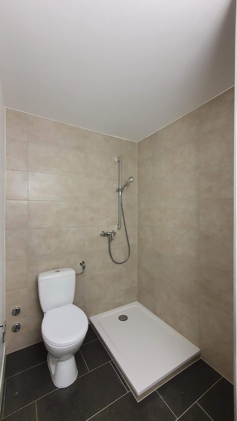 modern bathroom, tiled floor, white toilet, walk-in shower, showerhead