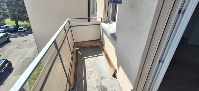 access to balcony, shadowed area, parked cars in the background