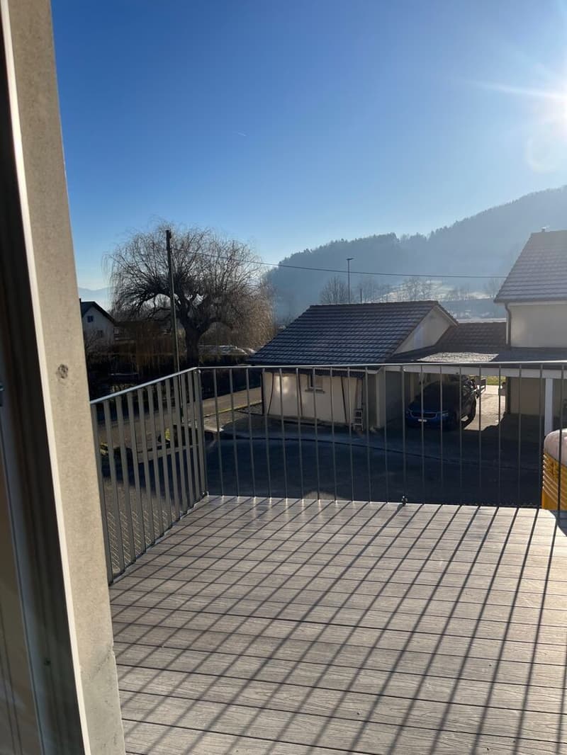 Balcony with wooden deck, metal railings, with view of the road and mountains