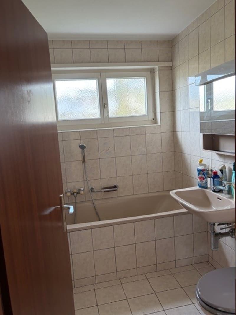 Bathroom with bathtub, sink, toilet, and windows