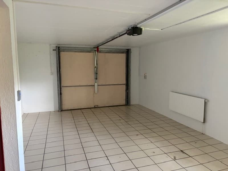 Empty room with white tiles, white walls, garage door, and a white radiator