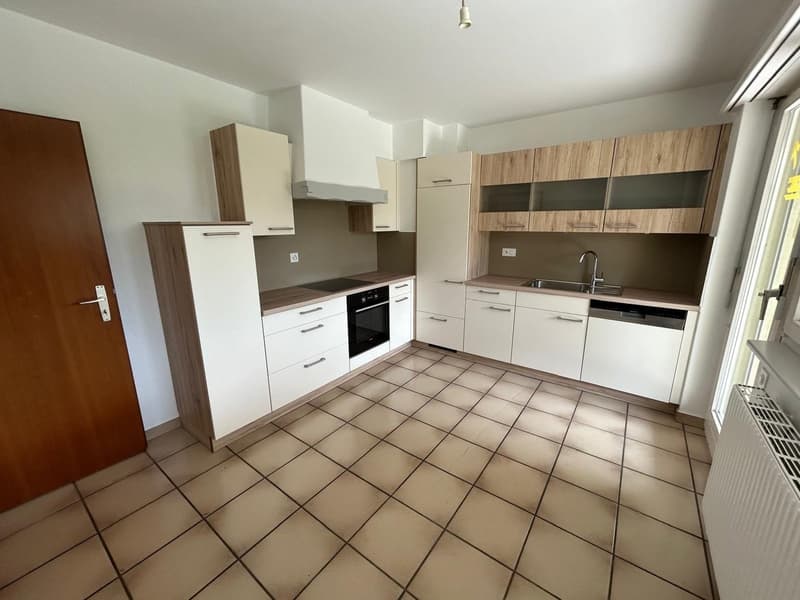 modern kitchen with white cabinets, tiled floor, stainless steel sink, dishwasher, oven, and a wooden door