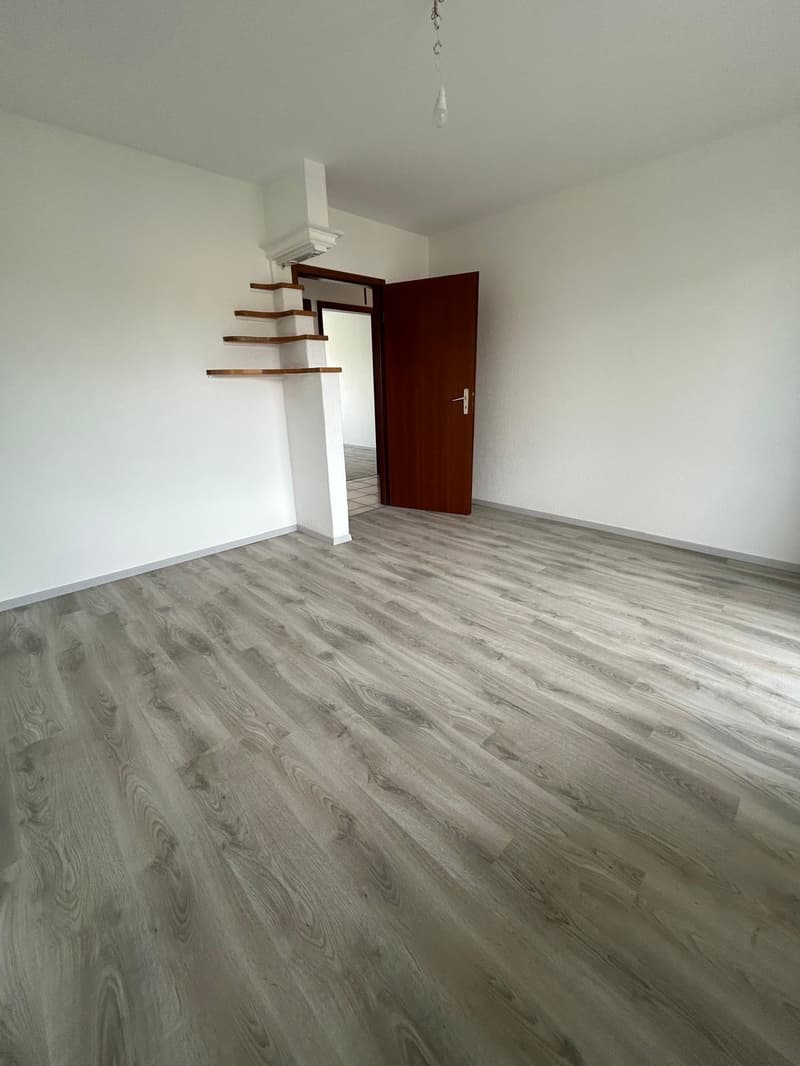 empty room, wooden door, white walls, wooden floor, open door leading to another room
