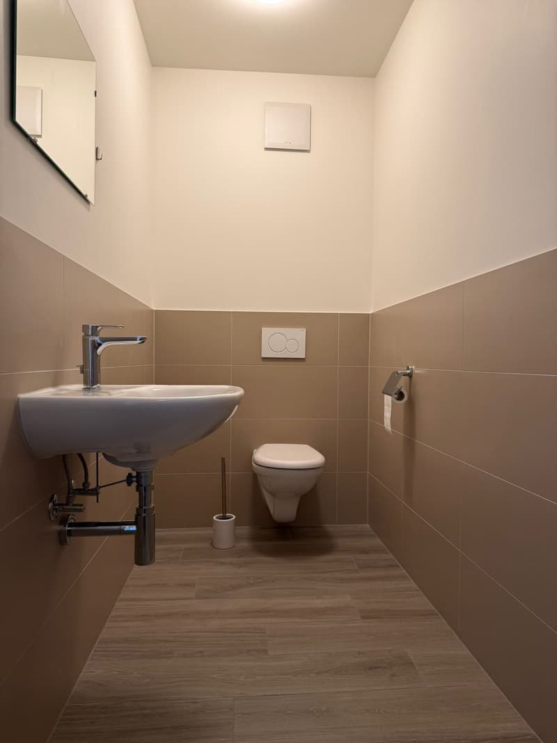 Bathroom: white sink, silver faucet, white toilet, tiled walls, wooden floor