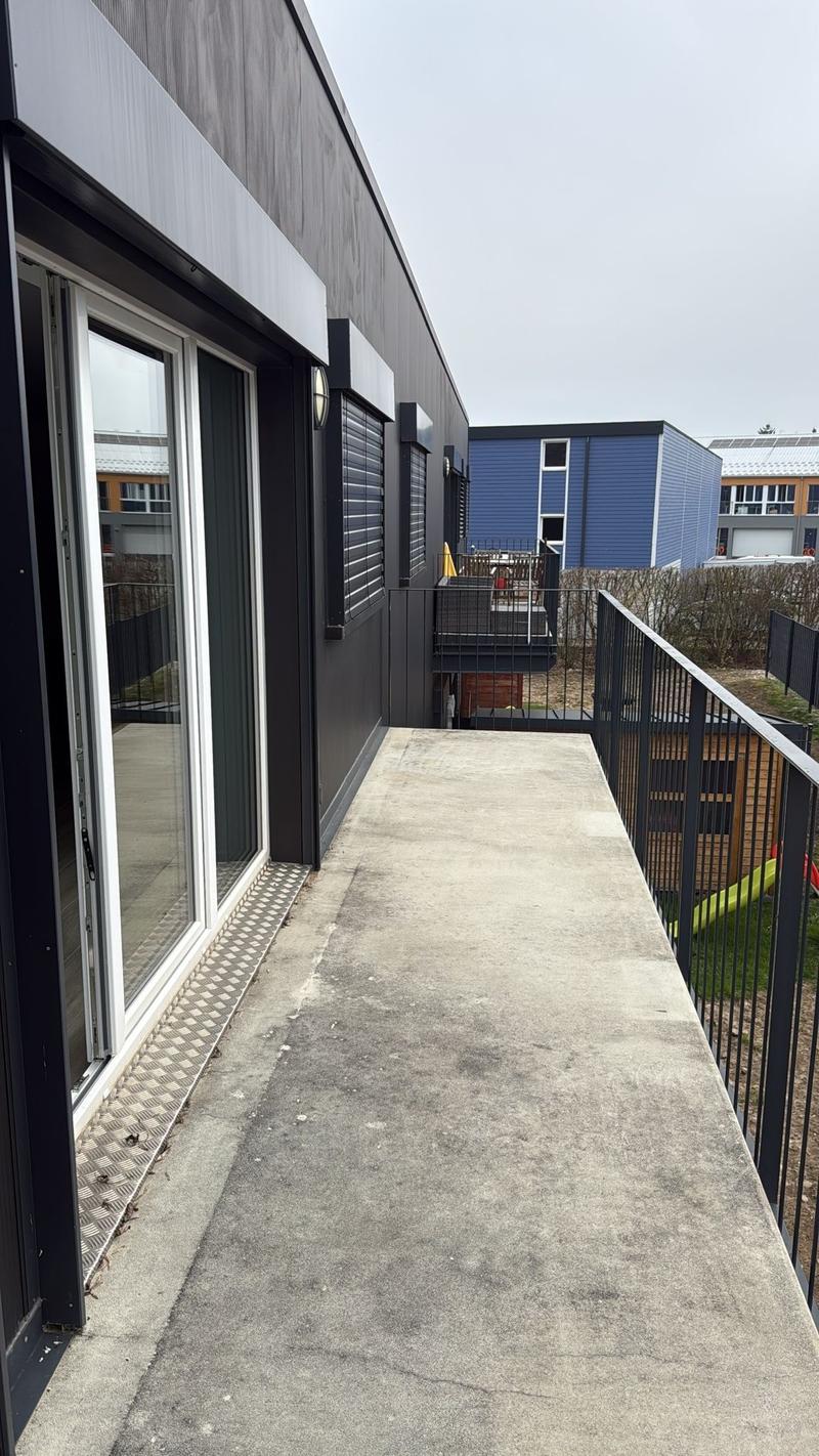 Balcony, Black railings, a small yard with a wooden shed, a slide, a bush fence