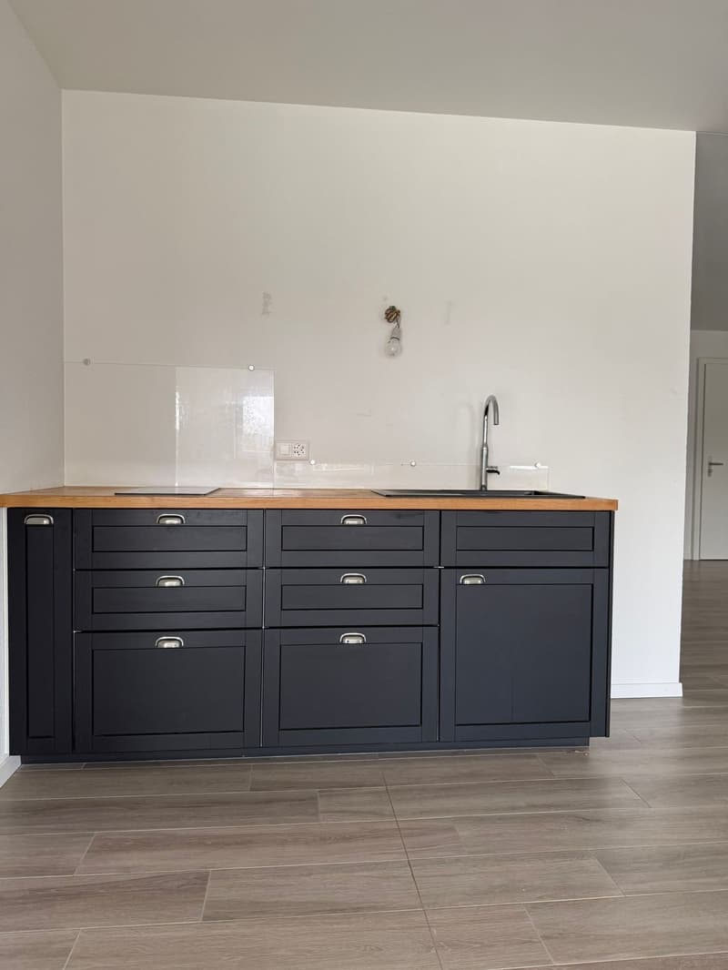 kitchen: dark cabinets, wooden countertop, sink, faucet, empty room, tiled floor