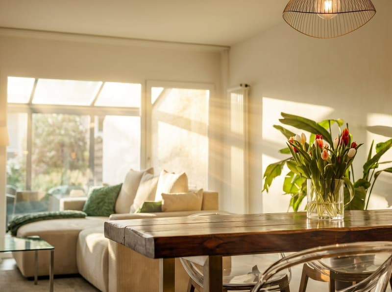 living room with sofa, coffee table, dining table, flowers, windows