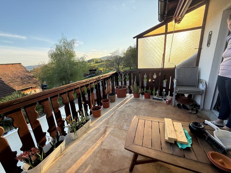 balcony with wooden railing, wooden table, potted plants, wooden chair, view of the landscape