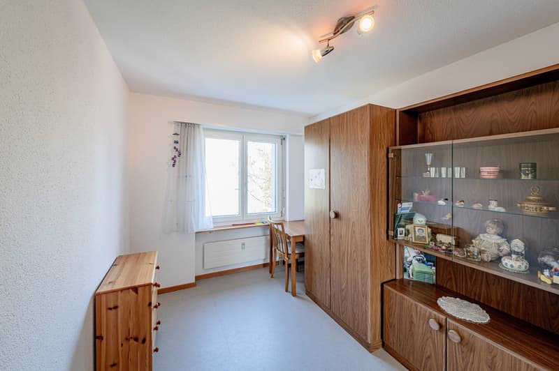 wooden furniture, white walls, window with white curtains, wooden desk, wooden cabinet, glass cabinet